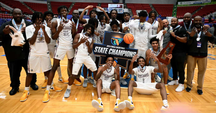 Miami Norland players and coaches gather around the Class 5A state championship basketball trophy on Friday after beating Tampa Blake for the title at the RP Funding Center.